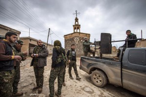 Fighters of the Kurdish People's Protection Units (YPG) stand near a pick-up truck mounted with an anti-aircraft weapon in front of a church in the Assyrian village of Tel Jumaa, north of Tel Tamr town February 25, 2015. Kurdish militia pressed an offensive against Islamic State in northeast Syria on Wednesday, cutting one of its supply lines from Iraq, as fears mounted for dozens of Christians abducted by the hardline group. The Assyrian Christians were taken from villages near the town of Tel Tamr, some 20 km (12 miles) to the northwest of the city of Hasaka. There has been no word on their fate. There have been conflicting reports on where the Christians had been taken. REUTERS/Rodi Said (SYRIA - Tags: POLITICS CIVIL UNREST CONFLICT RELIGION TPX IMAGES OF THE DAY)