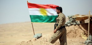 A peshmerga fighter stands next to a Kurdish flag as he guards a position near the strategic Jalawla area, in Diyala province, which is a gateway to Baghdad, as battles with Islamic State (IS) jihadists continue on August 25, 2014. Kurdish forces backed by Iraqi air support retook three villages in the Jalawla area, as well as a main road used by jihadists to transport fighters and supplies, peshmerga members said. AFP PHOTO / ALI AL-SAADI