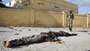 A Somali soldier walks past the bodies of two suspected al-Shabab fighters who were killed while engaging in a car bomb attack in the capital Mogadishu, Somalia Sunday, June 21, 2015. The al-Qaida-linked al-Shabab extremist group tried to attack a training compound used for intelligence officials in Mogadishu, a police officer said. (AP Photo)