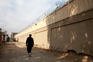 A guard walks to the entrance of the women's section inside Nangarhar Prison, Afghanistan. December 16, 2014. Gabriela Maj for the New York Times.