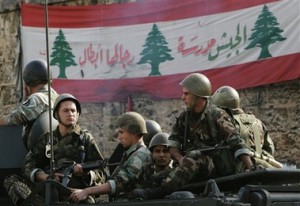 Lebanese soldiers backdropped by a Lebanese flag with Arabic writing that reads: "the army is a school, its man are brave," sit atop an armored personnel carrier as they watch a small group of taxi drivers protesting against the rise in fuel prices in Beirut, Lebanon Wednesday, Nov. 28, 2007. Army commander Gen. Michel Suleiman said Monday that "security measures taken in all parts of the country are to secure the presidential election." (AP Photo/Hussein Malla)
