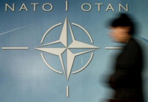 A woman walks past the NATO logo at the entrance of the Alliance headquarters ahead of a NATO foreign ministers meeting in Brussels December 4, 2003.  REUTERS/Thierry Roge