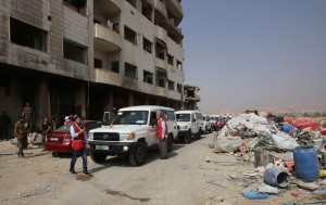 Red crescent ambulances and Syrian army soldiers gather in the government-controlled part of the besieged town of Daraya on August 26, 2016, as thousands of rebel fighters and civilians prepared to evacuate under an accord struck a day earlier.   An estimated 8,000 people remain in the town, despite a government siege lasting four years and regular regime bombardment.  / AFP PHOTO / Youssef KARWASHAN
