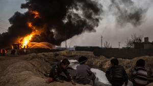 Young boys watch on as firefighters work to extinguish an oil well set on fire by fleeing ISIS members on November 9, 2016 in Al Qayyarah, Iraq. Many families have begun returning to their homes in recently liberated towns south of Mosul. Oil wells in the area that were set on fire by ISIS continue to burn blanketing the area in think clouds of smoke and oil.  (Chris McGrath/Getty Images)